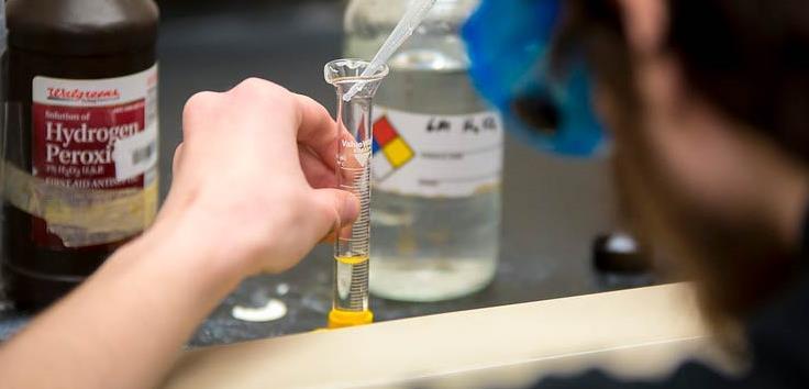 A student carefully measures into a glass beaker
