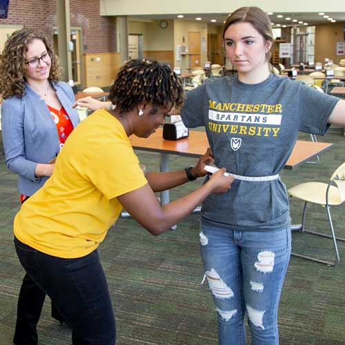Students measure on another during a class exercise.