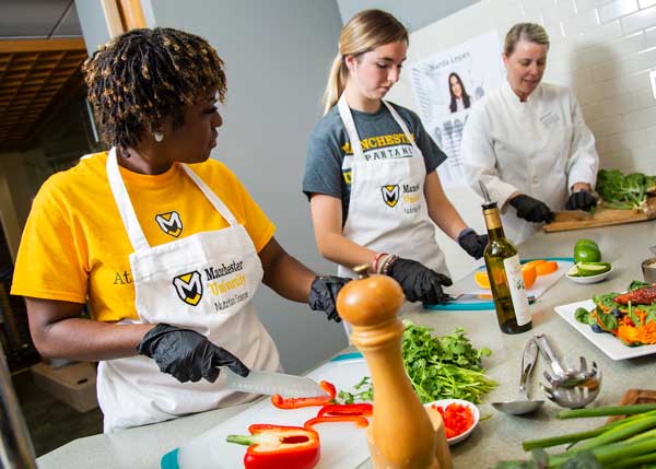 2 students and an instructor prepare food together
