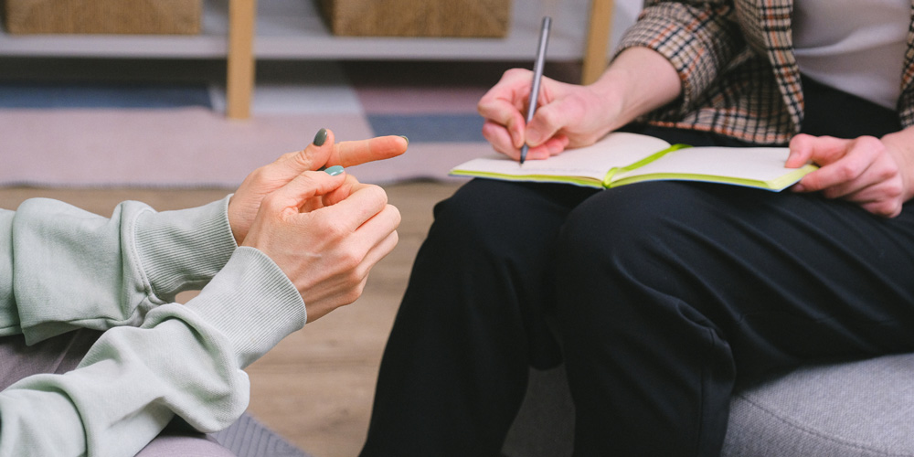 Stock image displays two people (hands only) during a counseling session.