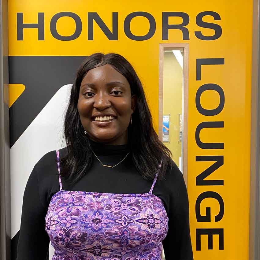 Sefunmi smiles for a photo in front of the Honors Lounge