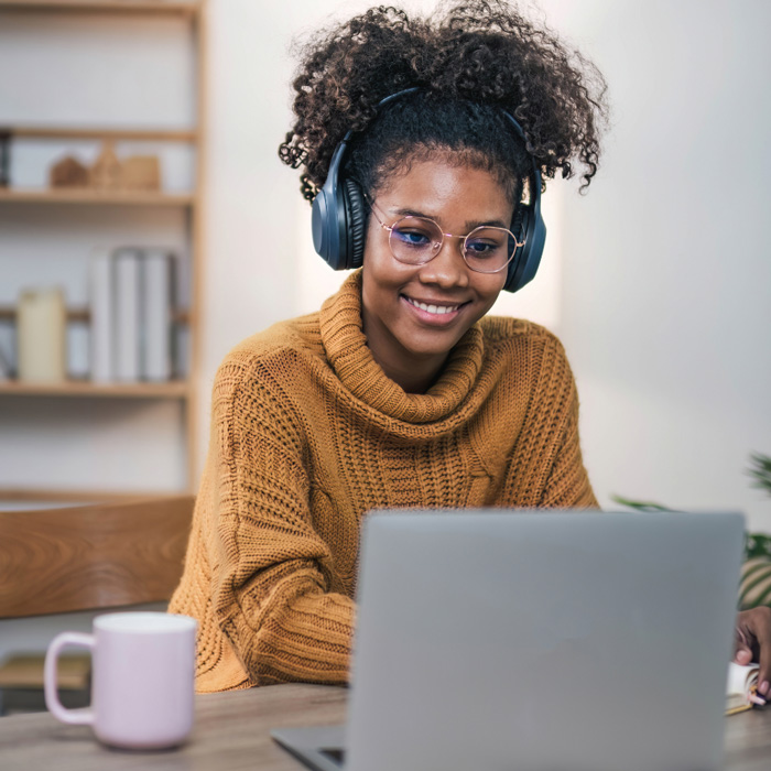 An adult online learner enjoys coffee at her laptop