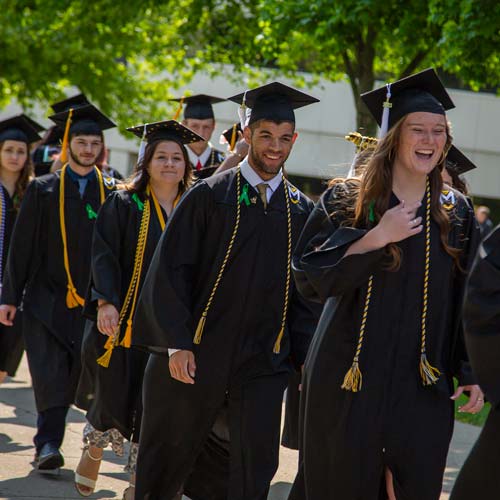 Image displays students walking proudly to graduate from MU