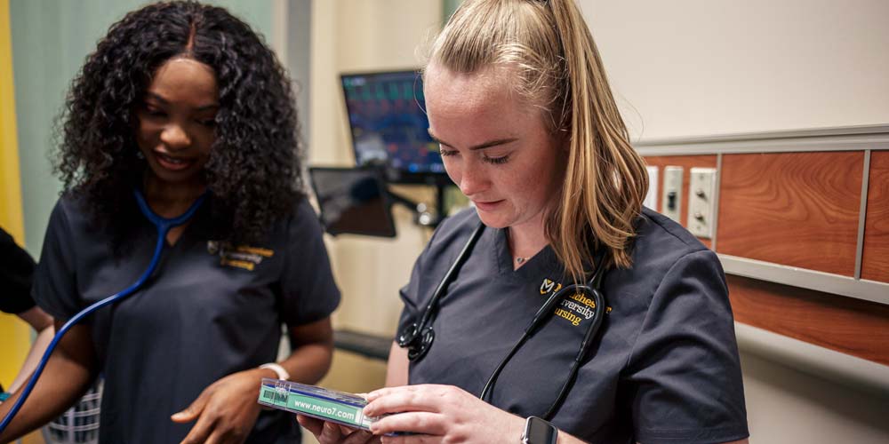 A nurse checks a label on the box during a lab exercise.