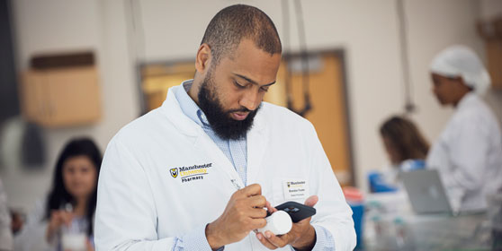 A student creates a label in the pharmacy lab