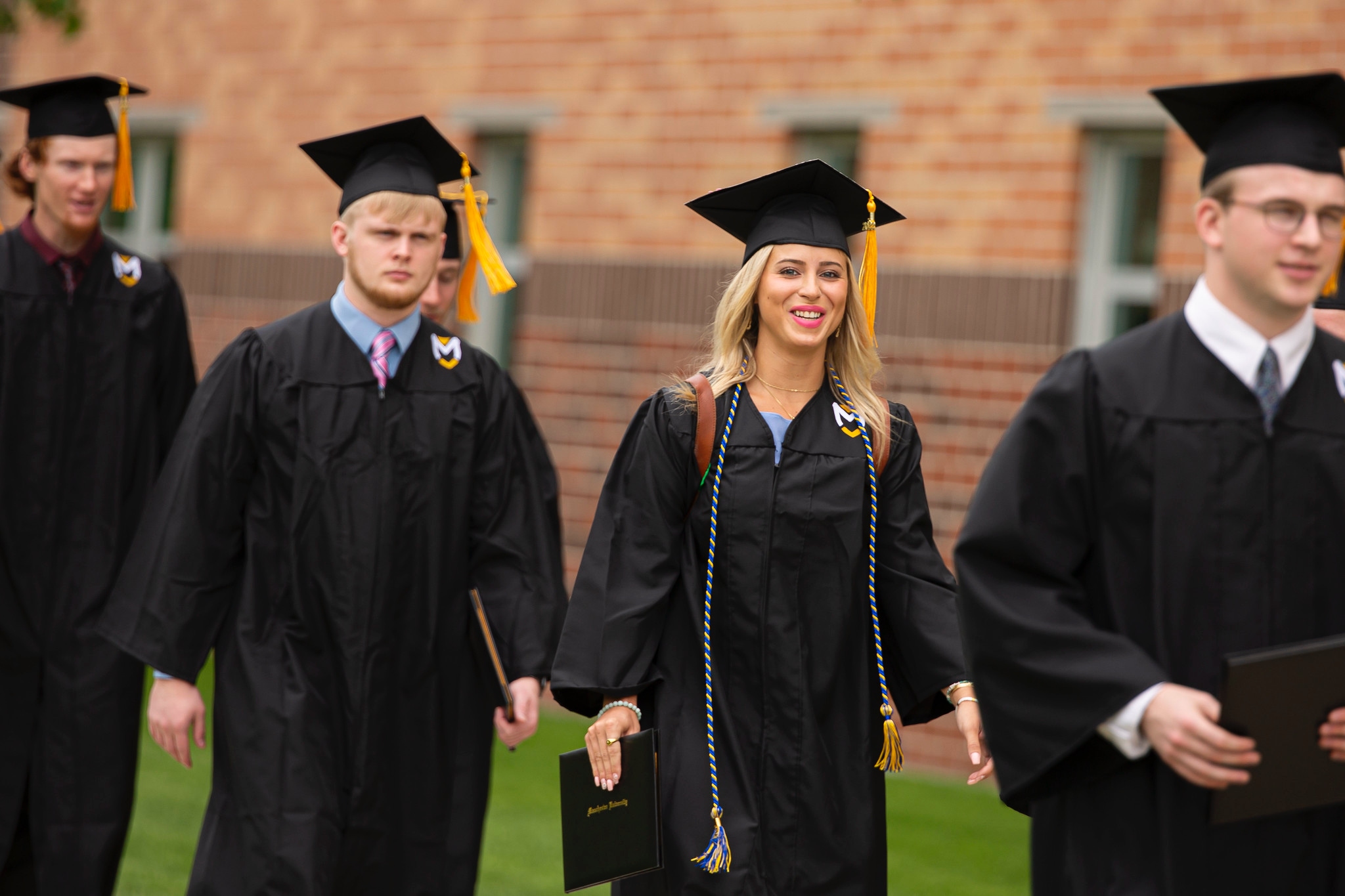 Commencement undergradaute students walking with diplomas