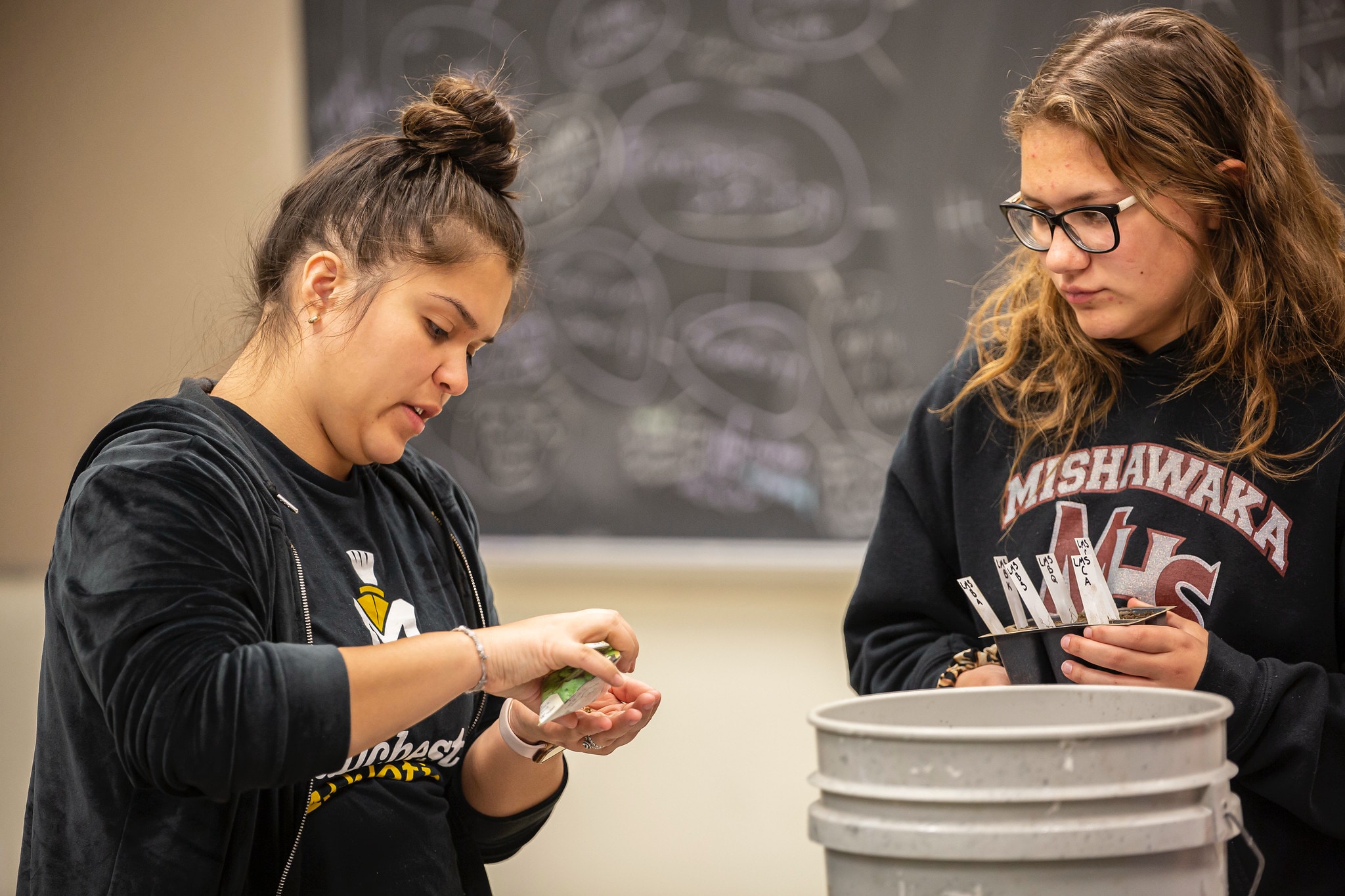 two female students inside in biology lab classroom with plants