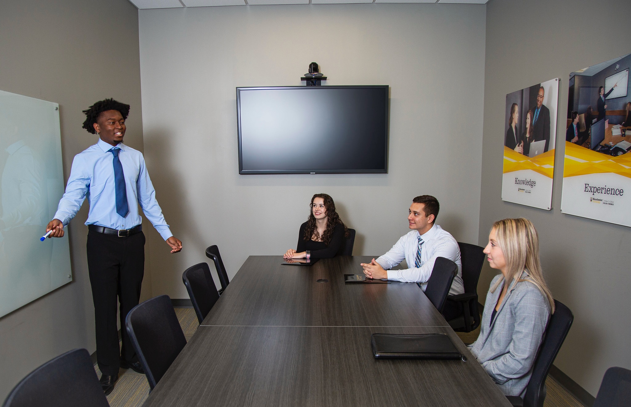 students in conference room walking with student a board students in conference room walking with student a board