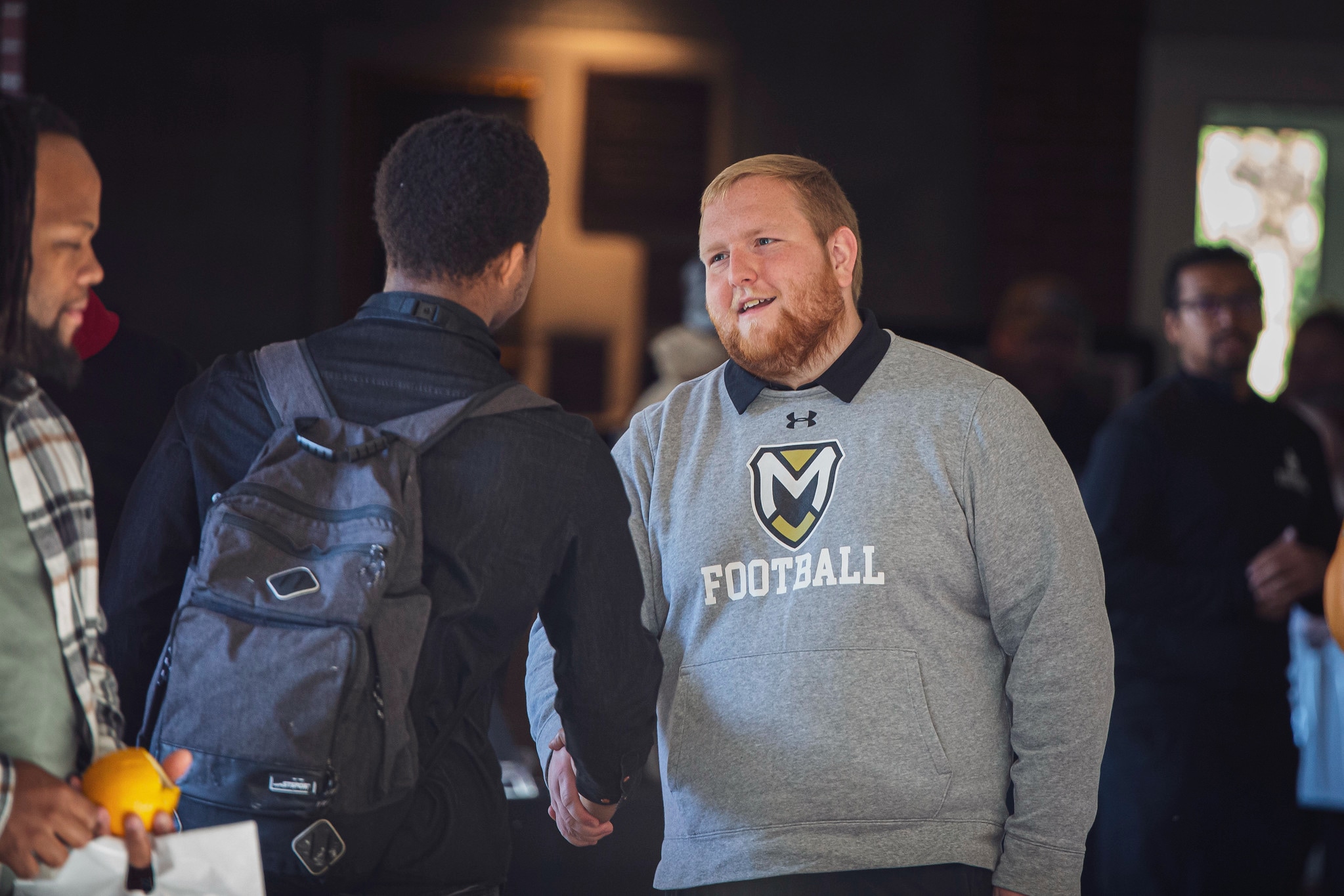 Campus Visit Day - male football student inside shaking hand male football student inside shaking hand