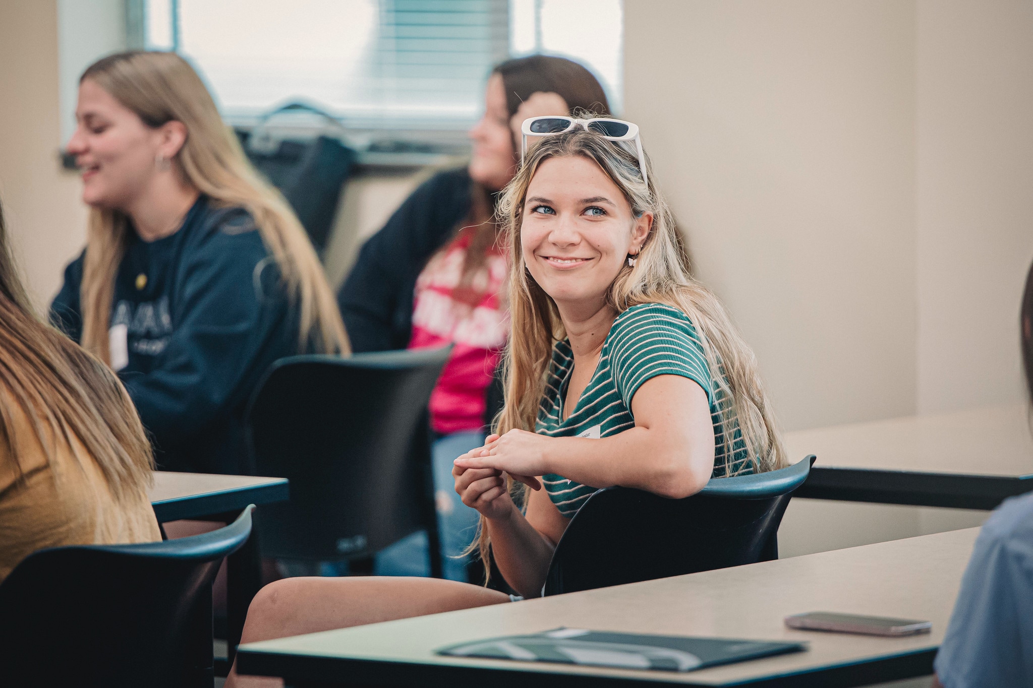 Campus Visit Day Black and Gold female student smiling in classroom with white sunglasses