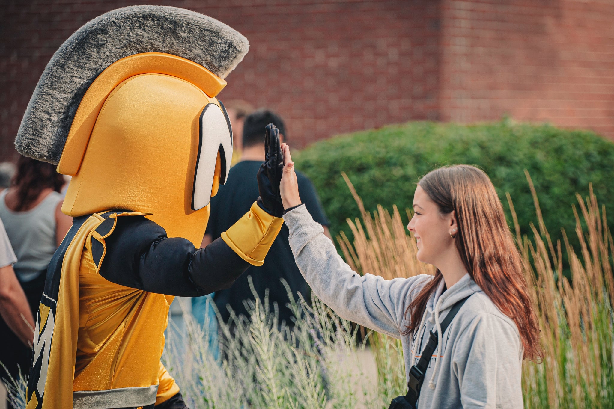Campus Visit Day student giving the mascot a high five