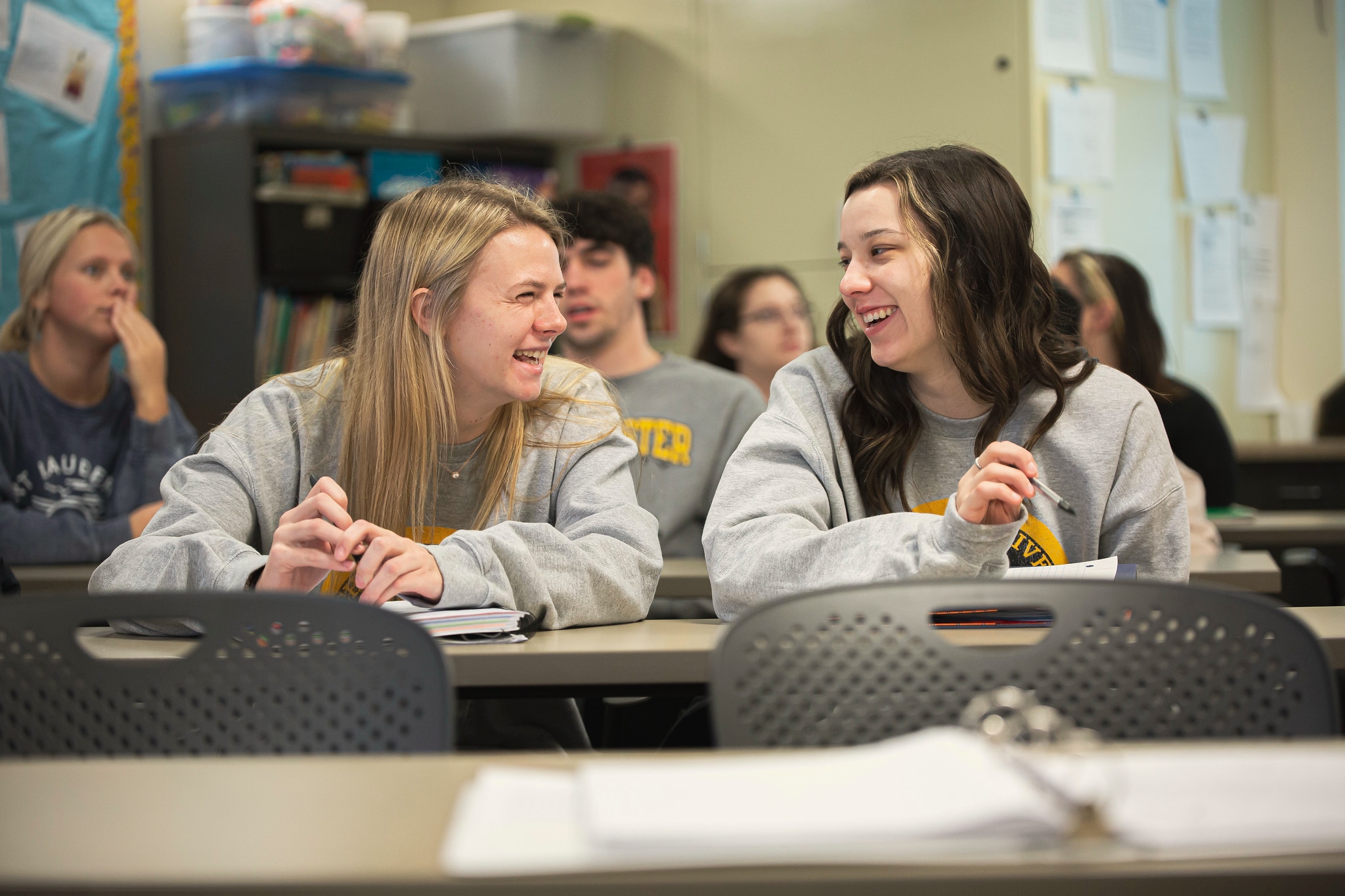 Education class inside with two female students smiling at each other