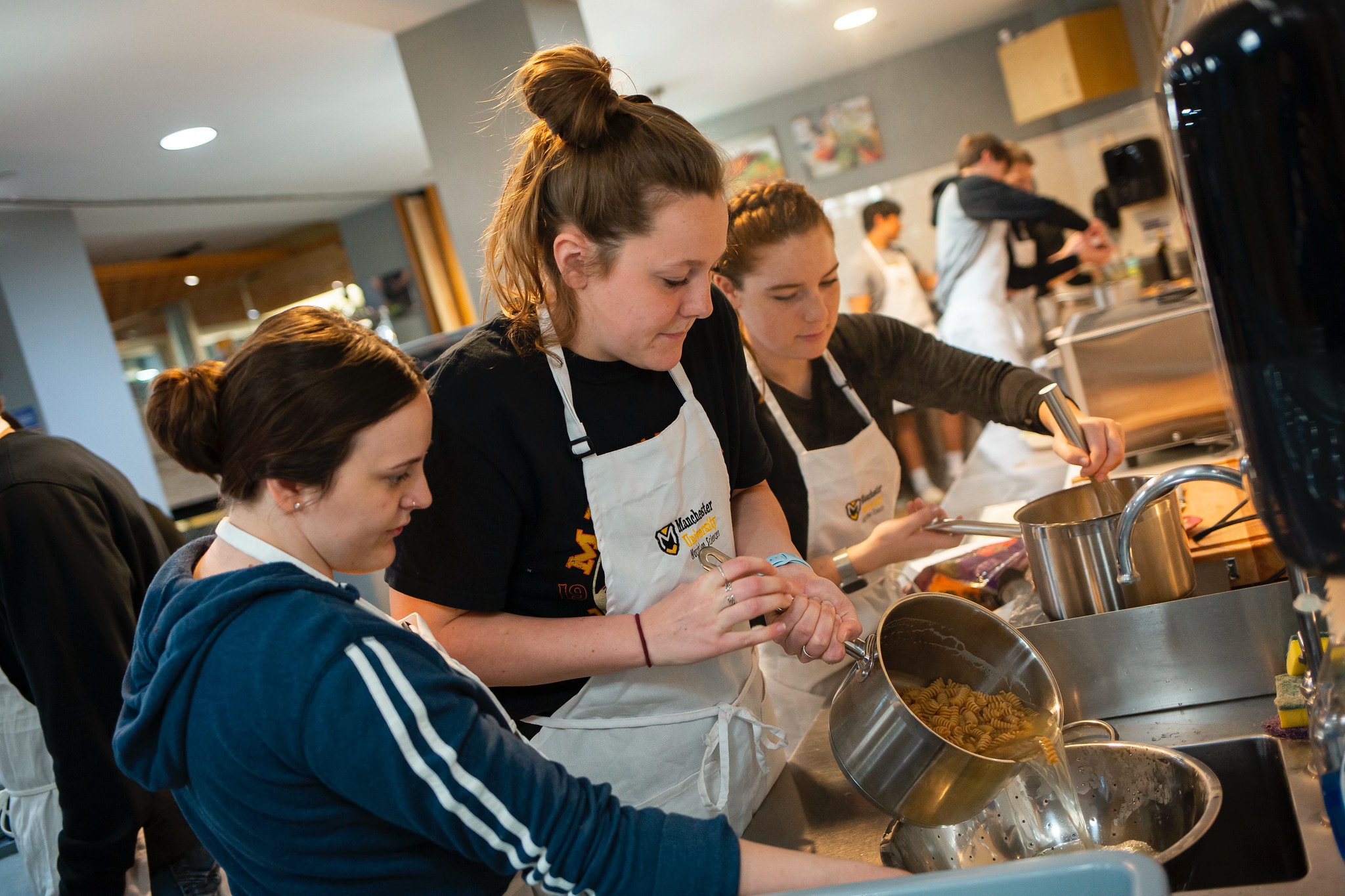 a group of female students prepare a pasta recipe during a nutrition class