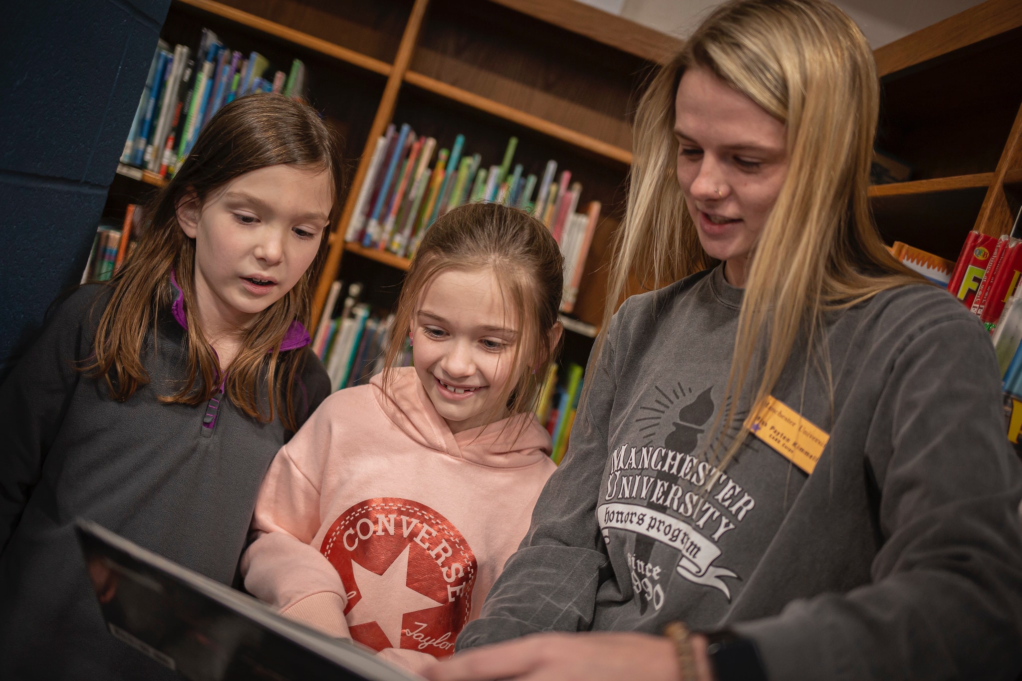 a manchester student teacher reads a book to two elementary students