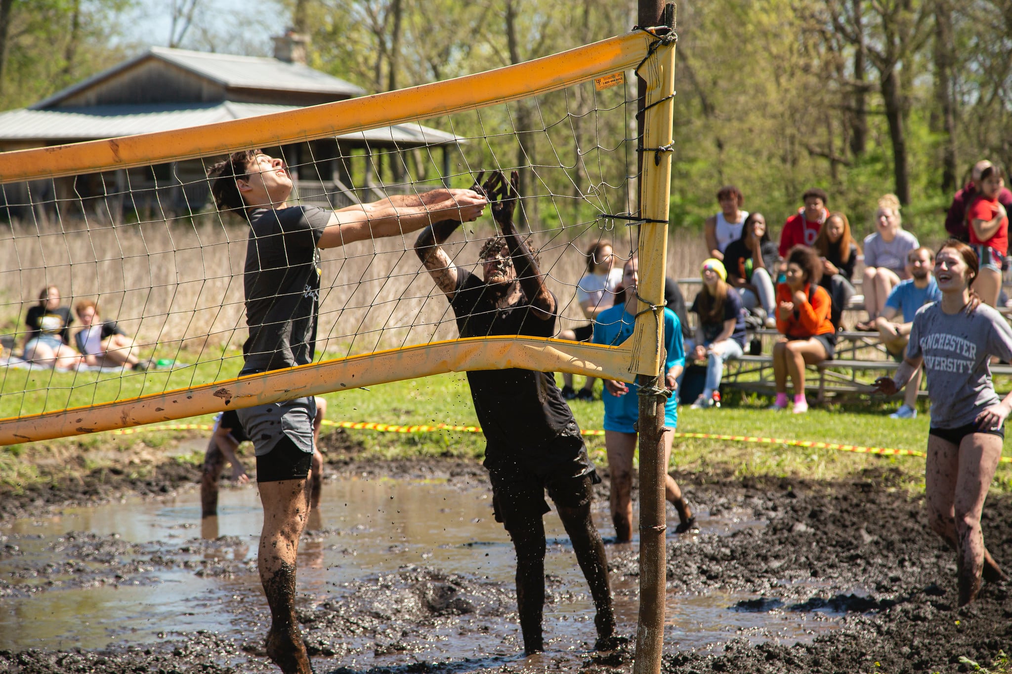 two male students prepare to return a volley during a game of mud volleyball