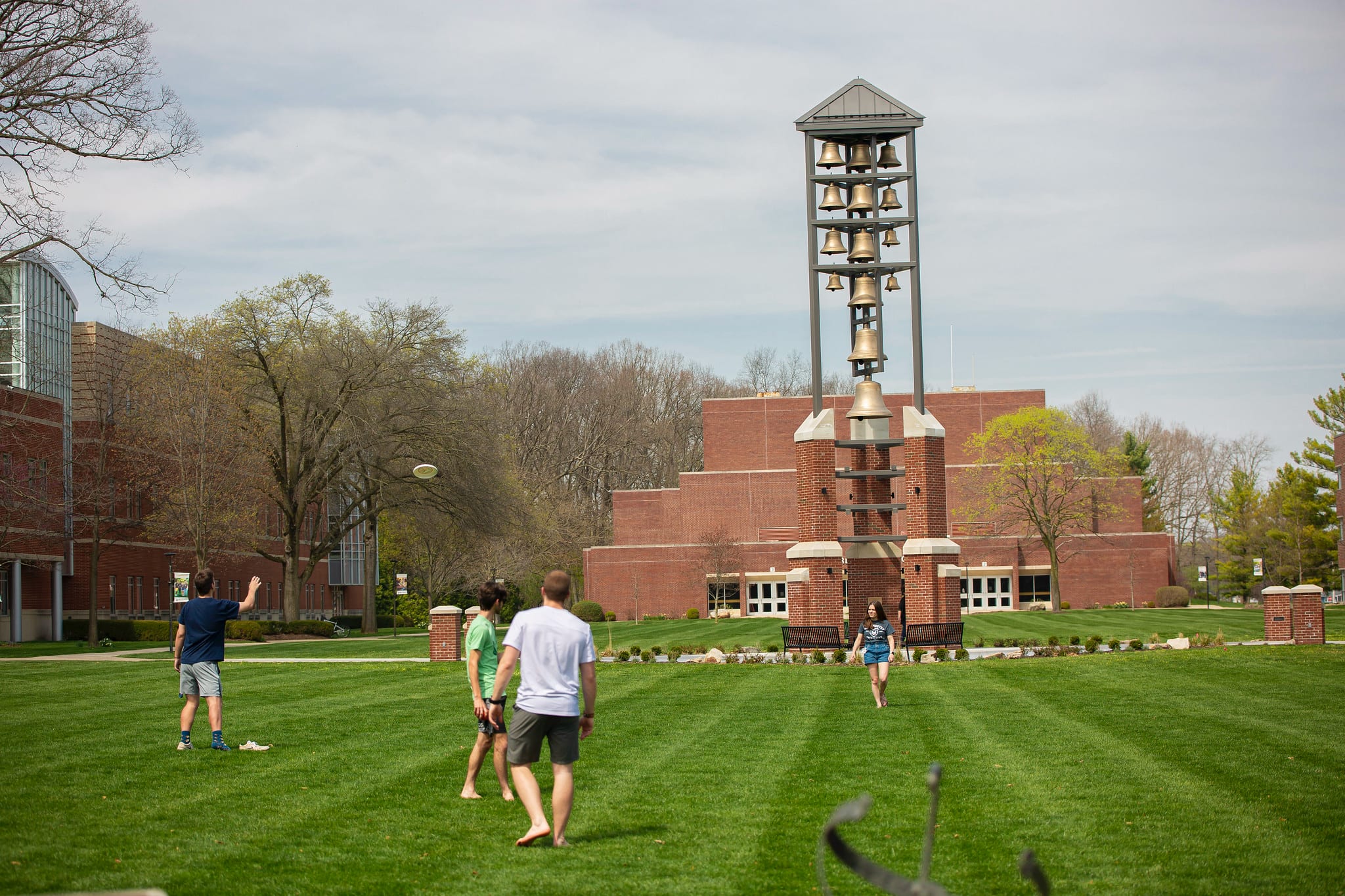 StudentActivities-5 students play with a frisbee in front of the manchester bell tower