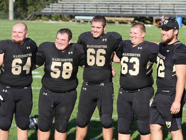 Eric Beard in football uniform with some teammates on the field