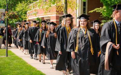 Graduates lined up walking down a sidewalk
