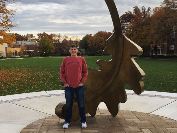 Nathan Timmerman standing by the oak leaf on campus
