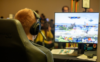 A student wears headphones while playing a video game