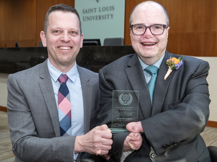 Dean W. Thomas Smith accepts glass plaque after being inducted into Saint Louis University School of Law Hall of Fame