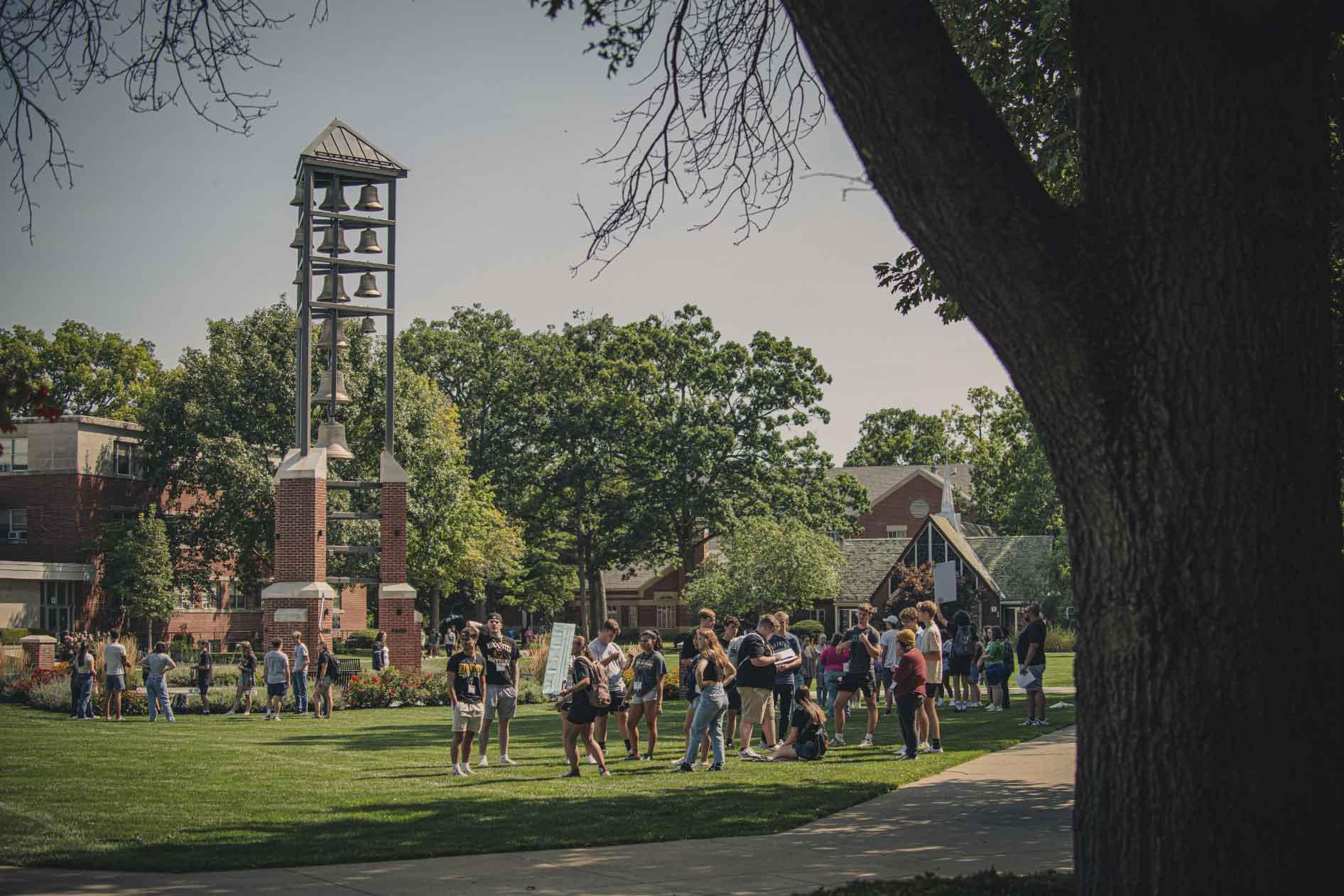 Group of students gathered outside on the lawn by a bell tower