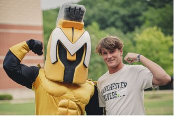 Male student flexes arm with Manny the mascot