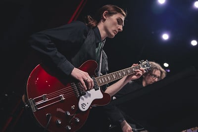 A male Manchester student plays a red hollow bodied electric guitar