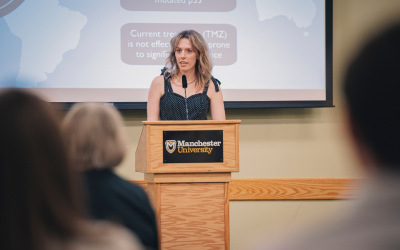 Woman speaks at podium with presentation