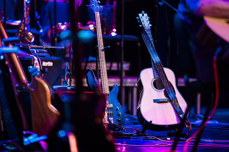 acoustic and electric guitars in stands on a stage