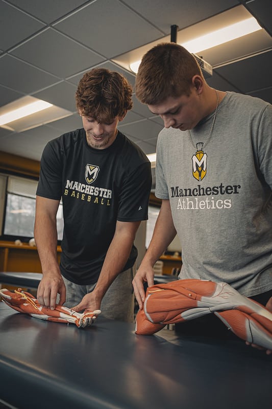 Two male students at Manchester University in a lab class learning about muscles in the body Two male students at Manchester University in a lab class learning about muscles in the body