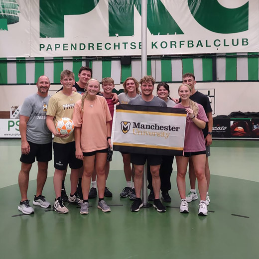 Netherlands-Korfball-Club Students stand proudly displaying an MU flag in front of the Netherlands Korfball Club during a January sessions trip with Dr. Jeff Beer.