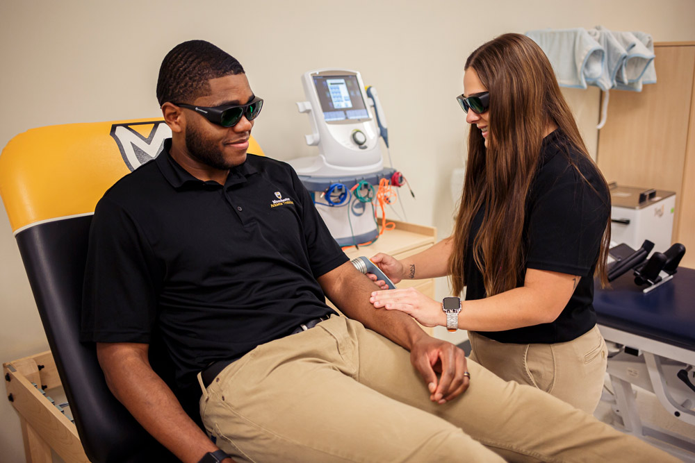 2 students work together to practice an elbow scan while wearing protective glasses