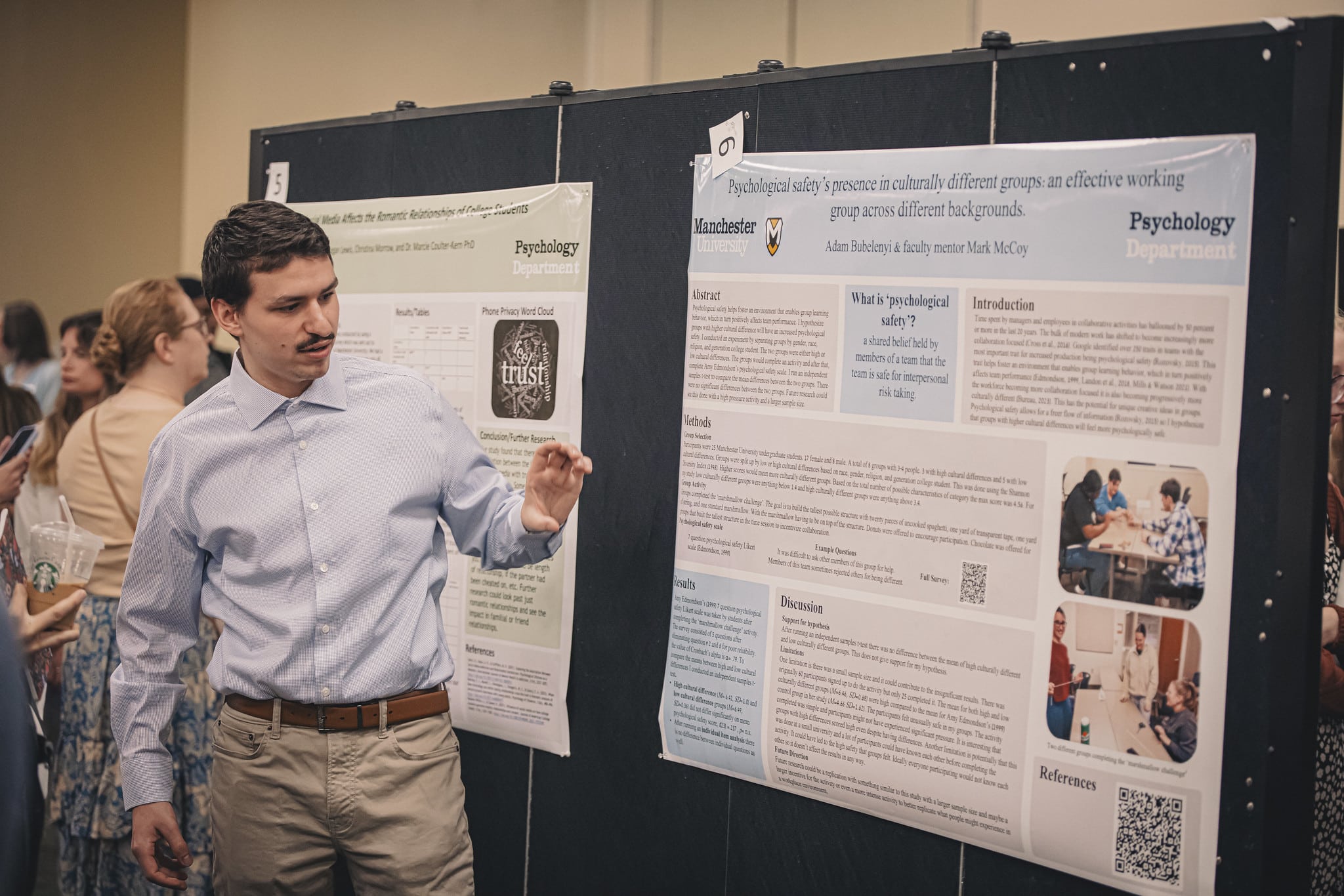 A male student with a mustache gives a presentation during the student symposium.