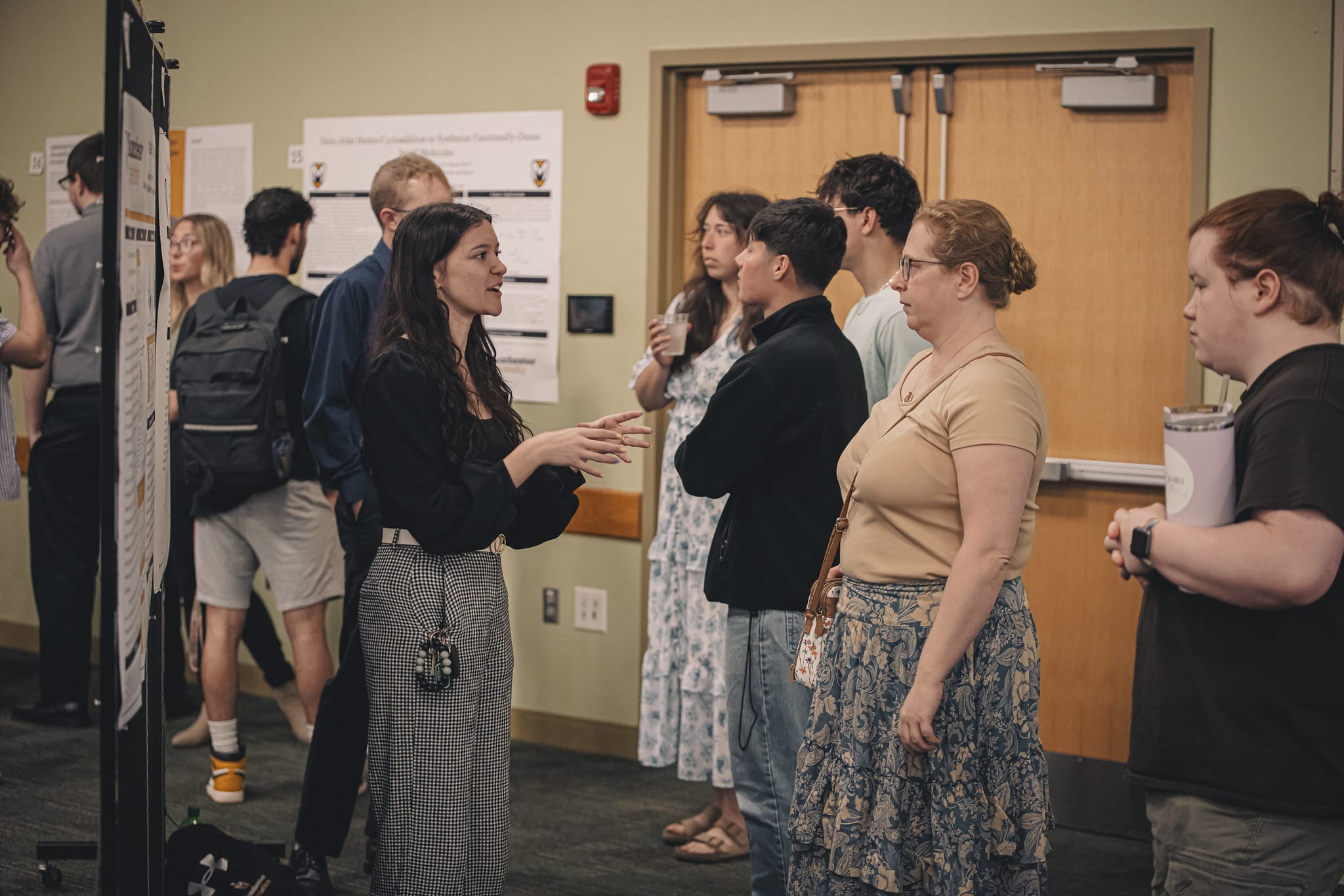 Female student shares her presentation to other students and faculty while standing in the foyer to the JYSC