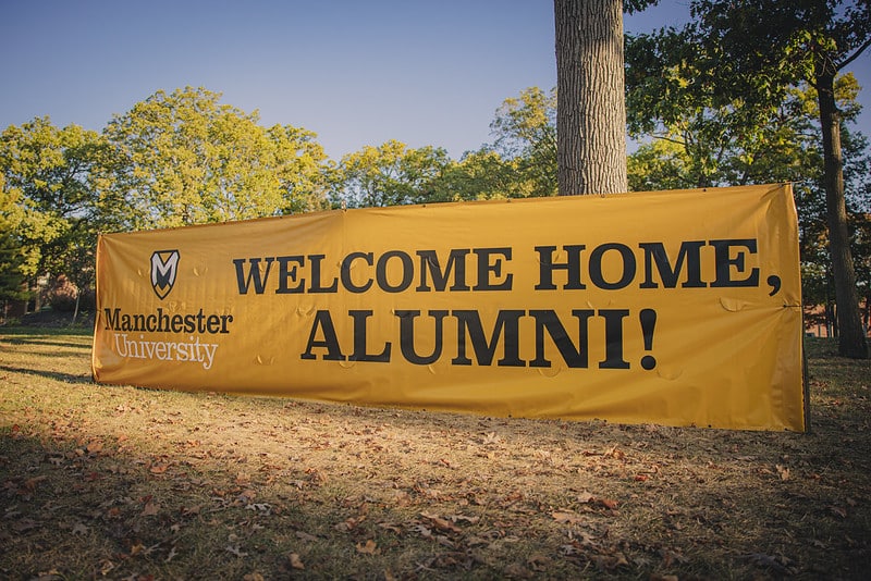 A giant gold sign reads "Welcome Home Alumni"