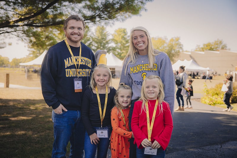 A family of four poses for a photo together at Homecoming