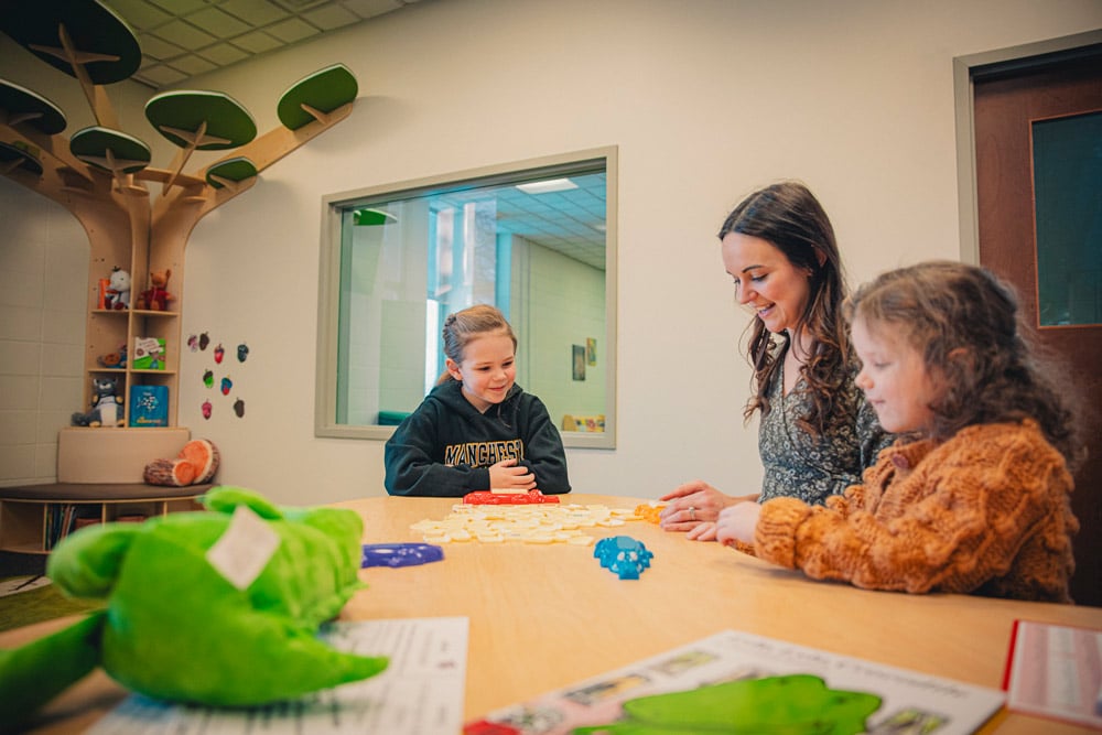 2 children read with an Manchester University Education Department student in the Learning Lab within Funderberg Library.