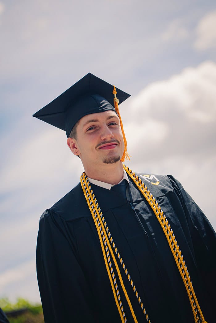Portrait_Male_Grad A male student graduates from Manchester University under a blue sky.