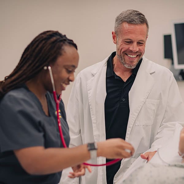 Dustin Diller works with a student in the nursing lab showcasing bedside nursing.