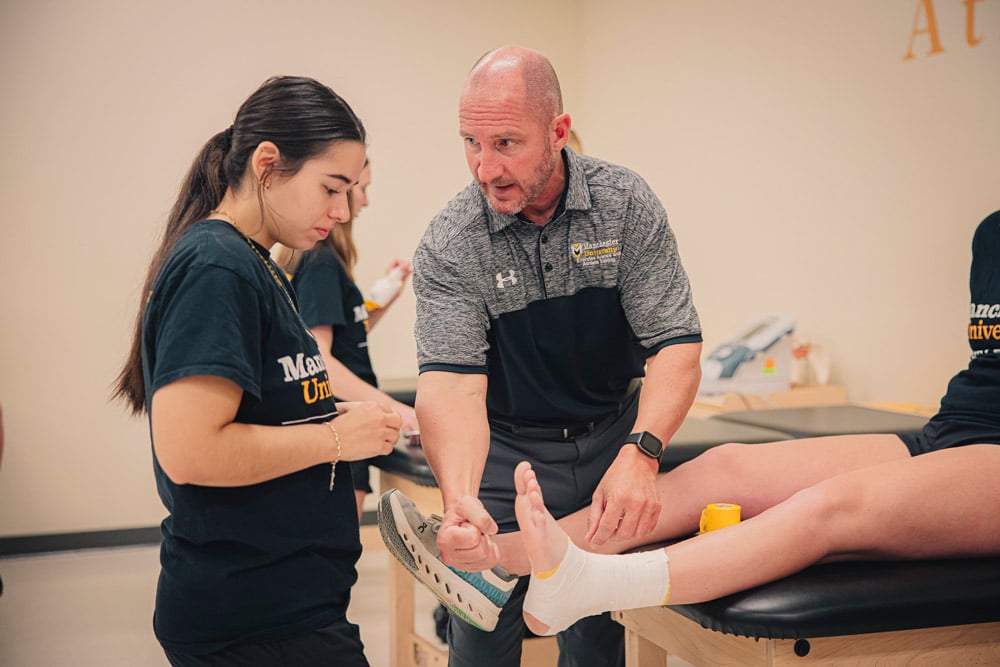 Dr. Beer instructs a female student in the Master of Athletic Training lab while demonstrating a foot wrap.