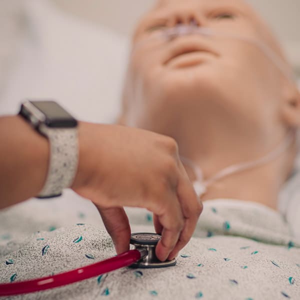 A Manchester University nursing student practices with a stethoscope in the Fort Wayne lab.