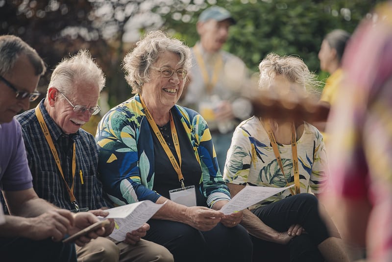 Manchester Alumni sit together and sing while smiling during an exclusive event.