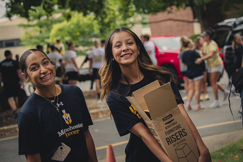 2 female students are helping with Week of Welcome's move in day.