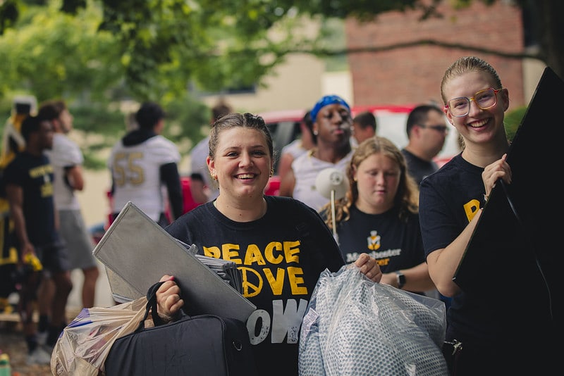 a group of students carry items during move-in day.