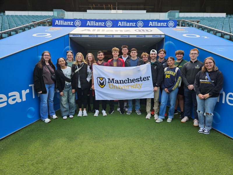 A photo from within the Allianz Rugby Team Stadium features the students who traveled to England