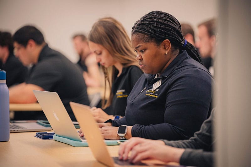 A female student sits with her laptop open in the Fort Wayne classroom environment for the Applied Pre-Physical Therapy Program.
