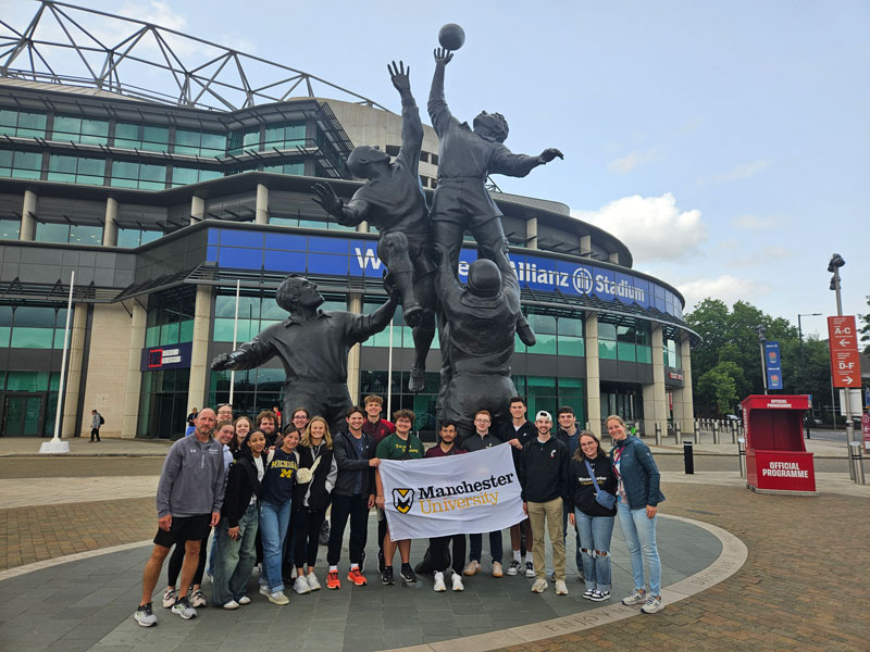 Students stand in front of the Rugby Stadium in England