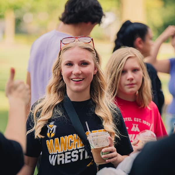 A female wrestling student holds a coffee while attending a visit day.