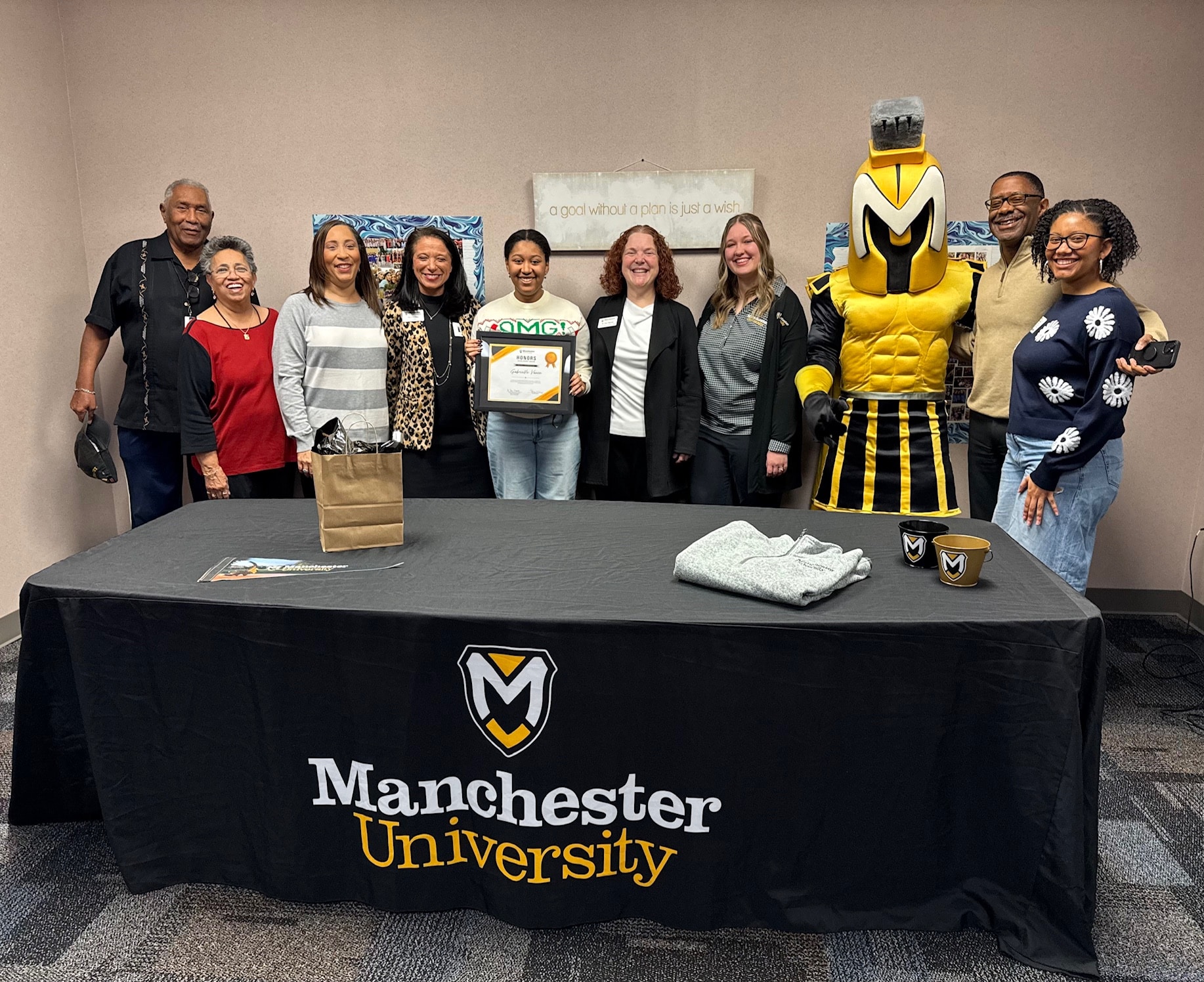 Gabrielle Vance with family, MU staff, and mascot Manny, receiving the full-ride Honors Scholarship.